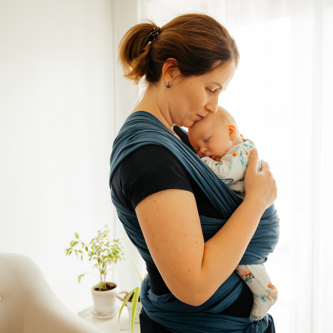A mother holding her baby close in a sling