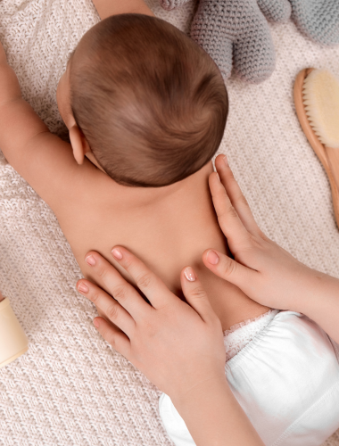 A baby receiving a back massage