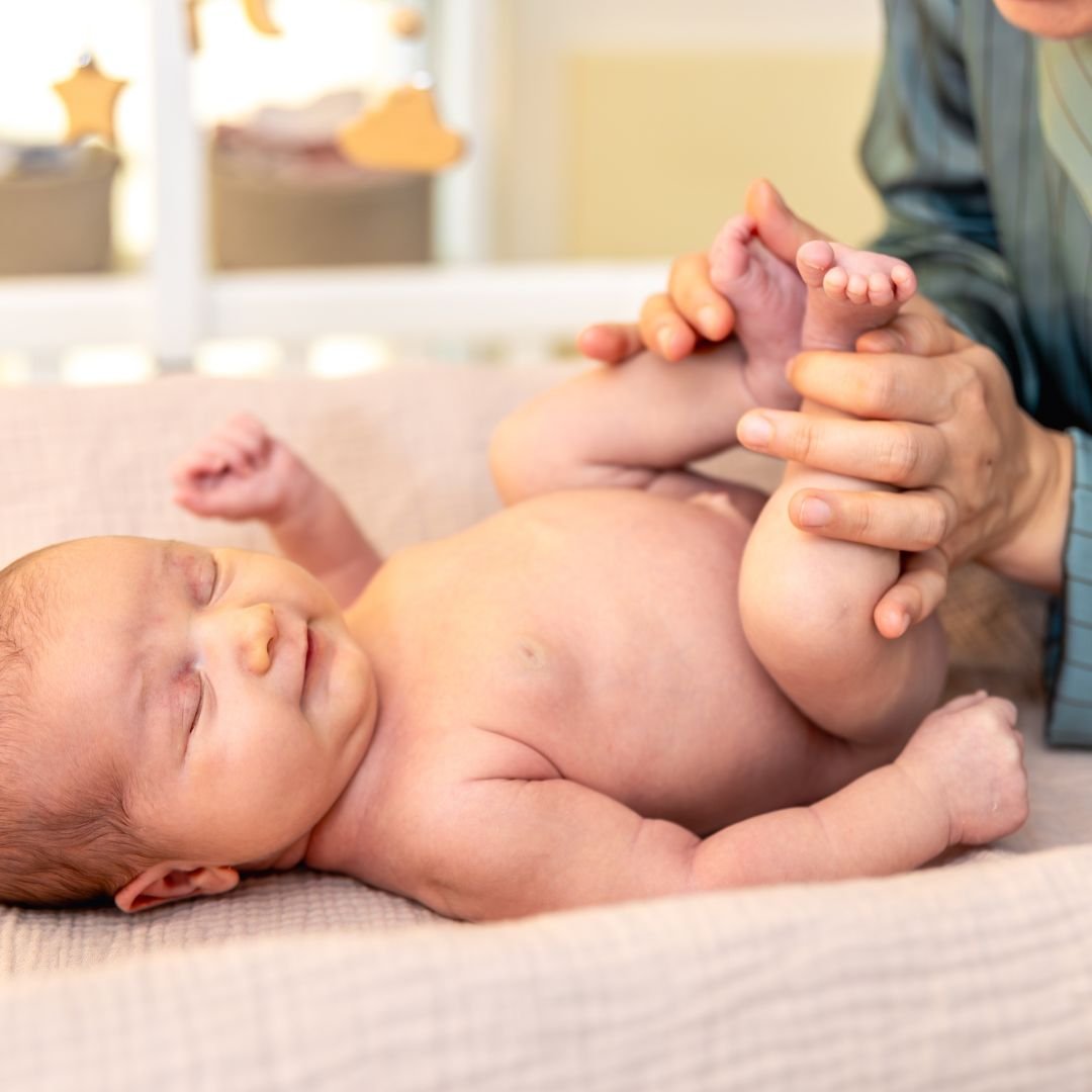 Hands gently massaging a newborn's legs